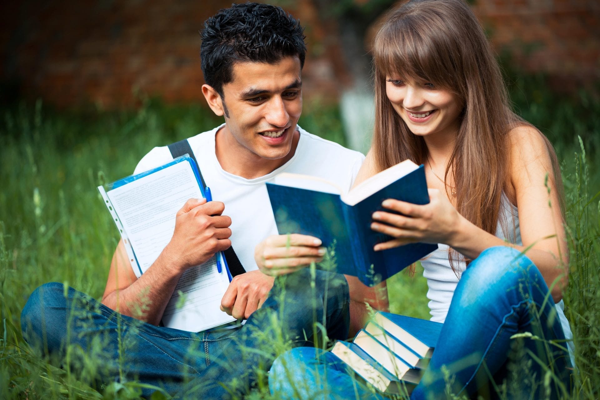 two-students-studying-in-park-on-grass-PD68WLH-min