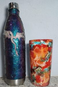 Left cup is irredecent with what looks like scales and a small white and glitter dragon. Right cup has red, blue, orange and green swirls that almost look like the surface of a planet.